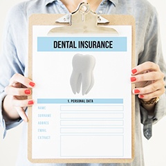 Holding a dental insurance form on a clipboard