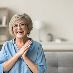 Senior woman sitting on couch clapping hands together