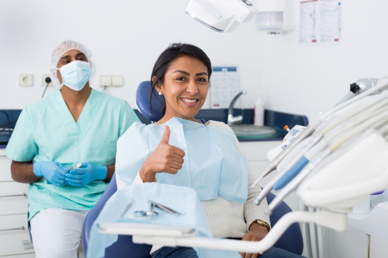 A woman giving the thumbs up sign in a dental chair